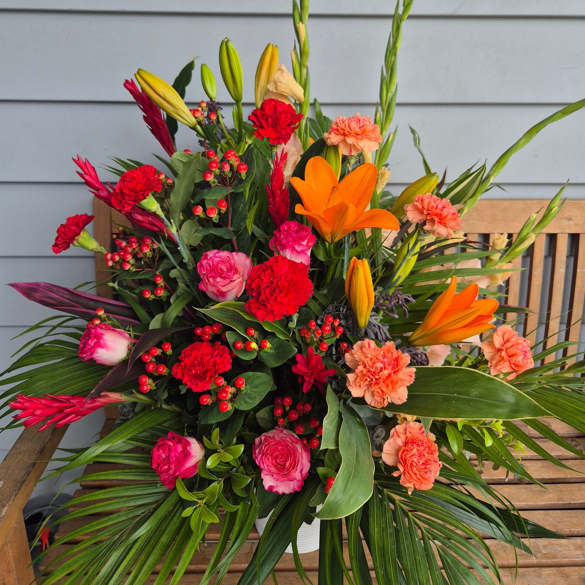 large floral arrangement with flowers in pinks red peaches and orange carnations roses lily